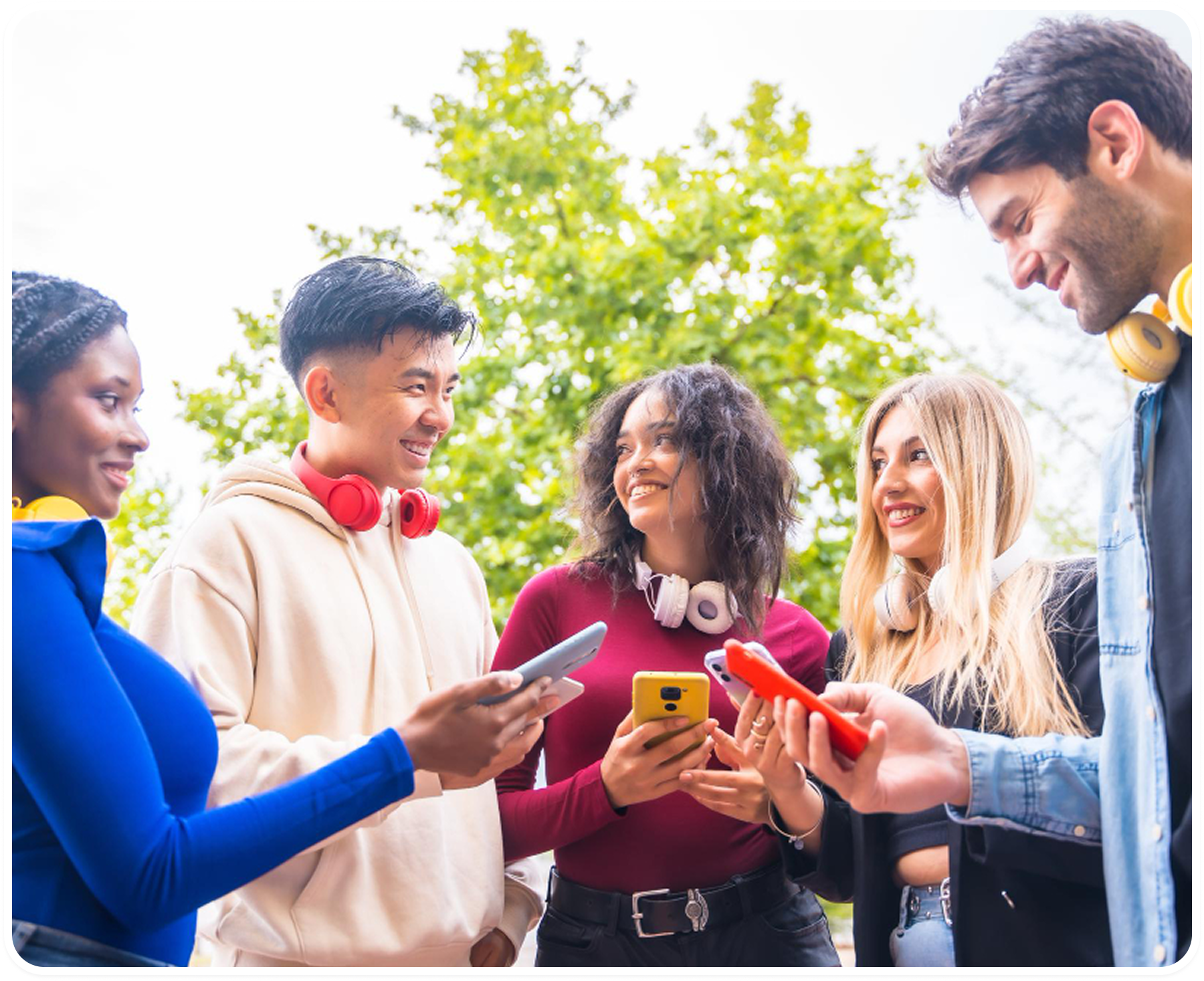 A group of friends laughing and looking at their phones